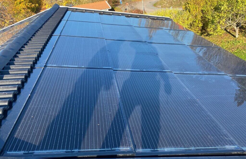 Monterade solceller Stockholm på hustak med grönska i bakgrunden