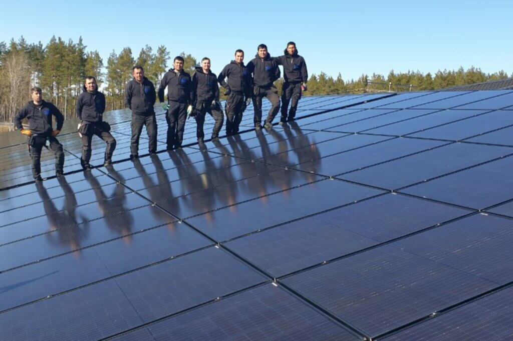 Solceller Stockholm montörer står på tak med solceller och tittar in i kameran